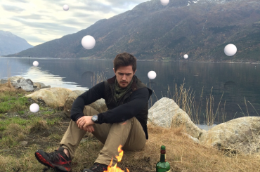 Pierce Brown sits by a camp fire